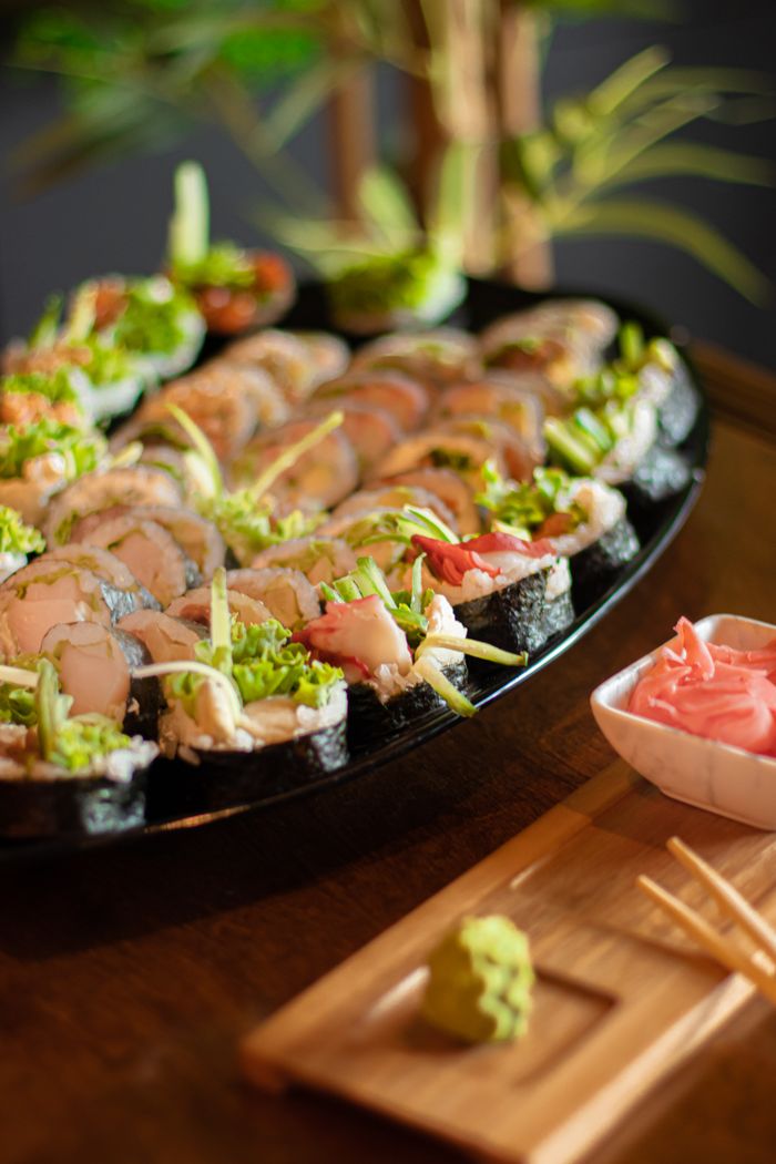 An elegant display of assorted sushi on a black platter with wasabi and ginger.