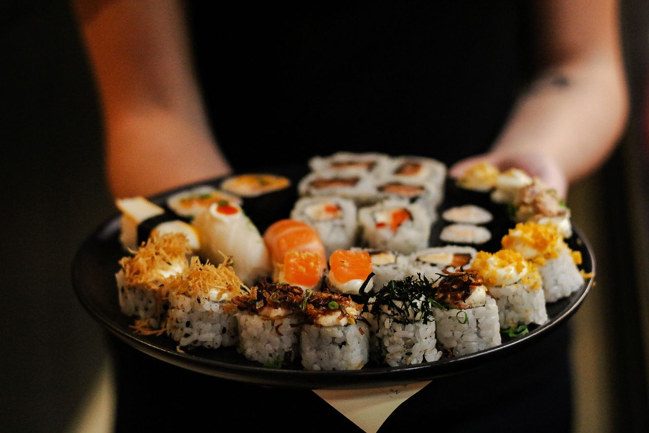 services-img Close-up of a variety of delicious sushi rolls on a black plate, showcasing vibrant ingredients.