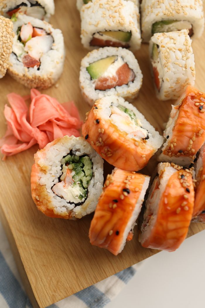 about-02 A delicious assortment of sushi rolls served on a wooden board with pickled ginger.