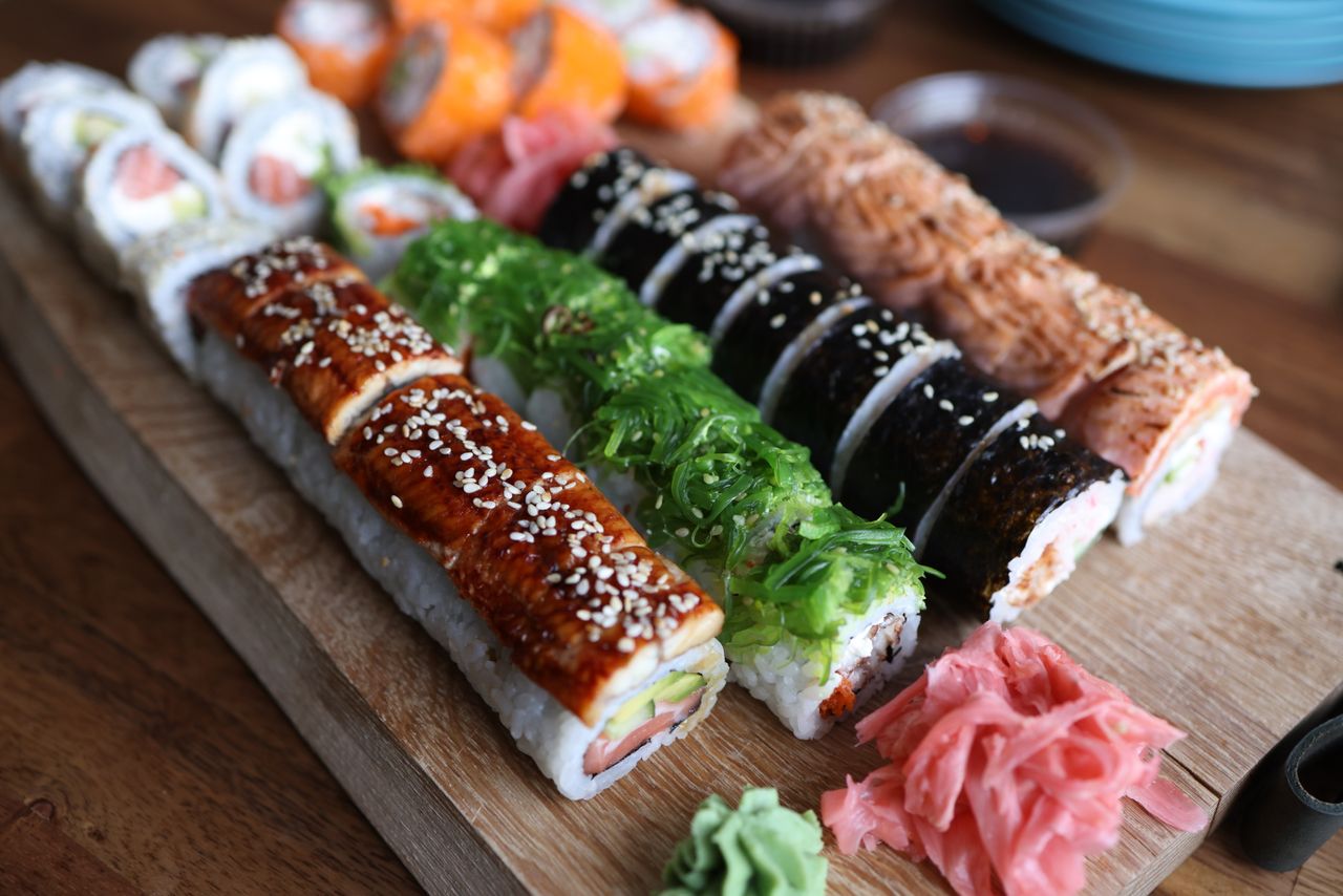 services-01 A delicious selection of sushi rolls with toppings like seaweed and sesame seeds on a wooden platter.