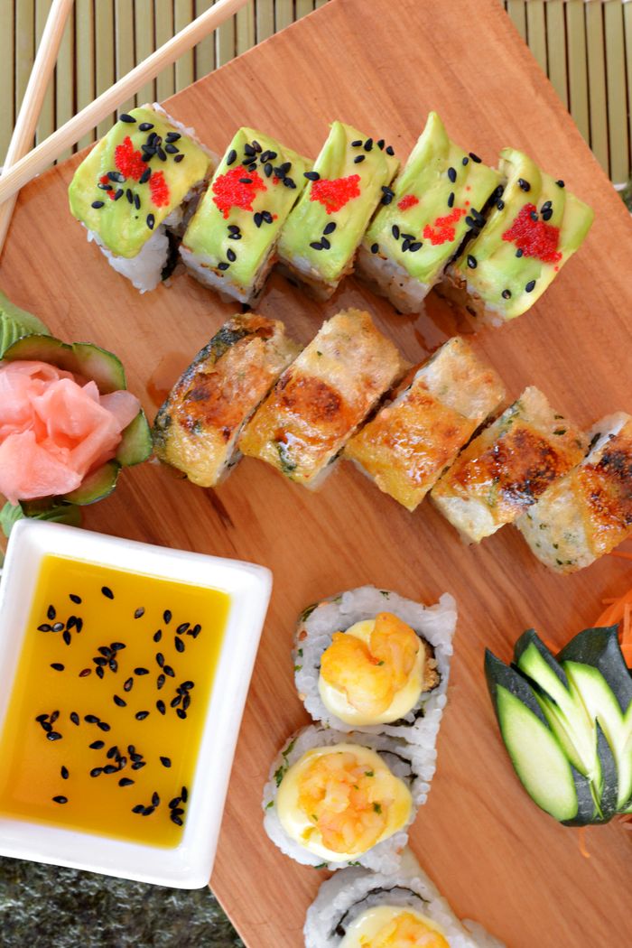 services-01 Delicious sushi rolls with avocado, eel, and shrimp, garnished with pickled ginger and sauce.
